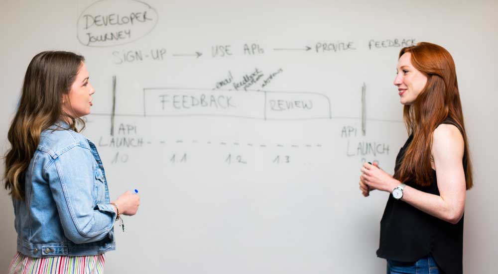 Two individuals discussing the development path of an applications feedback.